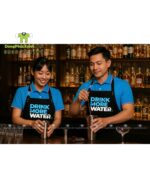 Tạp dề đồng phục nhân viên quán nước thiết kế dây móc khóa ngang eo độc đáo, in logo Drink More Water.
