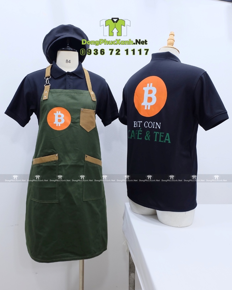Đồng phục nhân viên phục vụ quán cafe BIT COIN CAFÉ & TEA Bộ đồng phục quán cafe gồm áo thun đen có logo Bitcoin và tạp dề màu xanh rêu in logo Bit Coin Cafe & Tea.