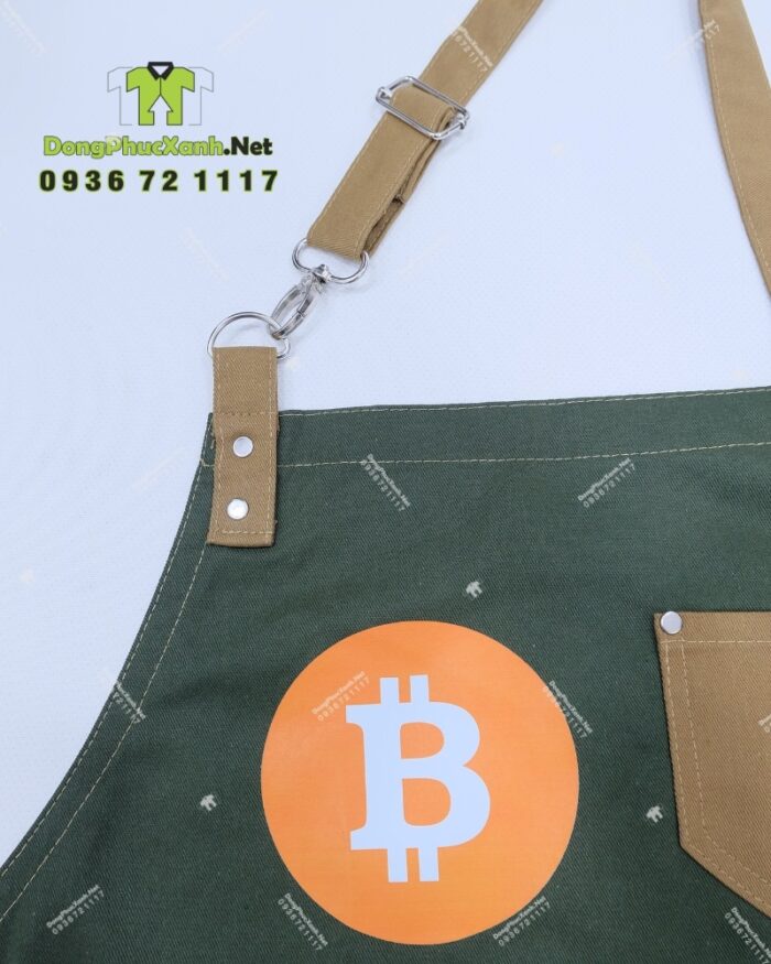 Bộ đồng phục quán cafe gồm áo thun đen có logo Bitcoin và tạp dề màu xanh rêu in logo Bit Coin Cafe & Tea.