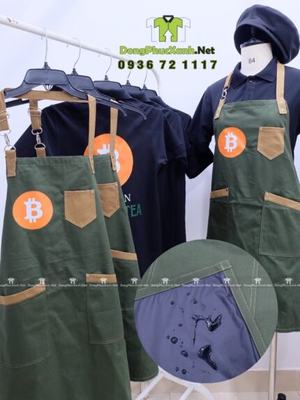 Bộ đồng phục quán cafe gồm áo thun đen có logo Bitcoin và tạp dề màu xanh rêu in logo Bit Coin Cafe & Tea.