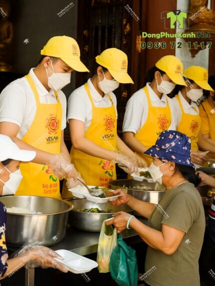 Tạp dề đồng phục dành cho các bếp nấu ăn màu vàng nổi bật, in logo Tường Nguyên và Vesak 2025.