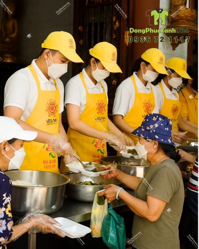 Tạp dề đồng phục dành cho các bếp nấu ăn màu vàng nổi bật, in logo Tường Nguyên và Vesak 2025.