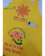 Tạp dề đồng phục dành cho các bếp nấu ăn màu vàng nổi bật, in logo Tường Nguyên và Vesak 2025.