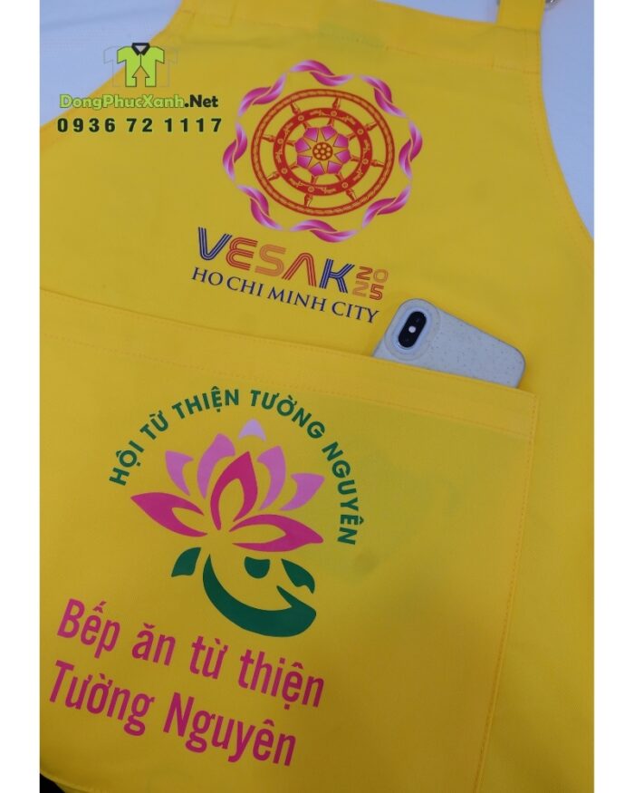 Tạp dề đồng phục dành cho các bếp nấu ăn màu vàng nổi bật, in logo Tường Nguyên và Vesak 2025.