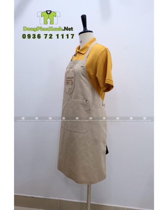 Tạp dề đồng phục nhân viên tiệm bánh màu be cổ điển, in logo Xưởng Bánh 1971’s.