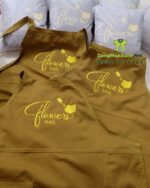 Tạp dề nail màu nâu đẹp dành cho nhân viên, thêu logo Flowers Nail.