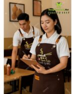 Tạp dề đồng phục dành cho nhân viên quán ăn màu nâu mộc mạc, in logo Phở Bò Thành Tuấn.