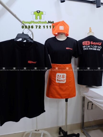 Bộ đồng phục SanU gồm áo thun đen, tạp dề cam và khăn tam giác