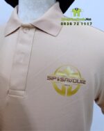 Bộ đồng phục gồm áo thun màu be và tạp dề đen, in logo Sip & Savour nổi bật