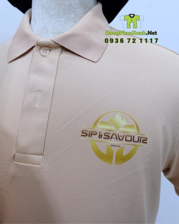 Bộ đồng phục gồm áo thun màu be và tạp dề đen, in logo Sip & Savour nổi bật