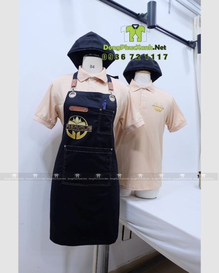 Bộ đồng phục gồm áo thun màu be và tạp dề đen, in logo Sip & Savour nổi bật