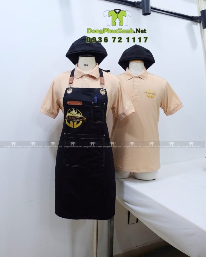 Bộ đồng phục gồm áo thun màu be và tạp dề đen, in logo Sip & Savour nổi bật
