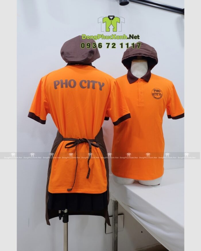 Bộ đồng phục quán ăn Pho City gồm áo thun cam và tạp dề nâu in logo nổi bật