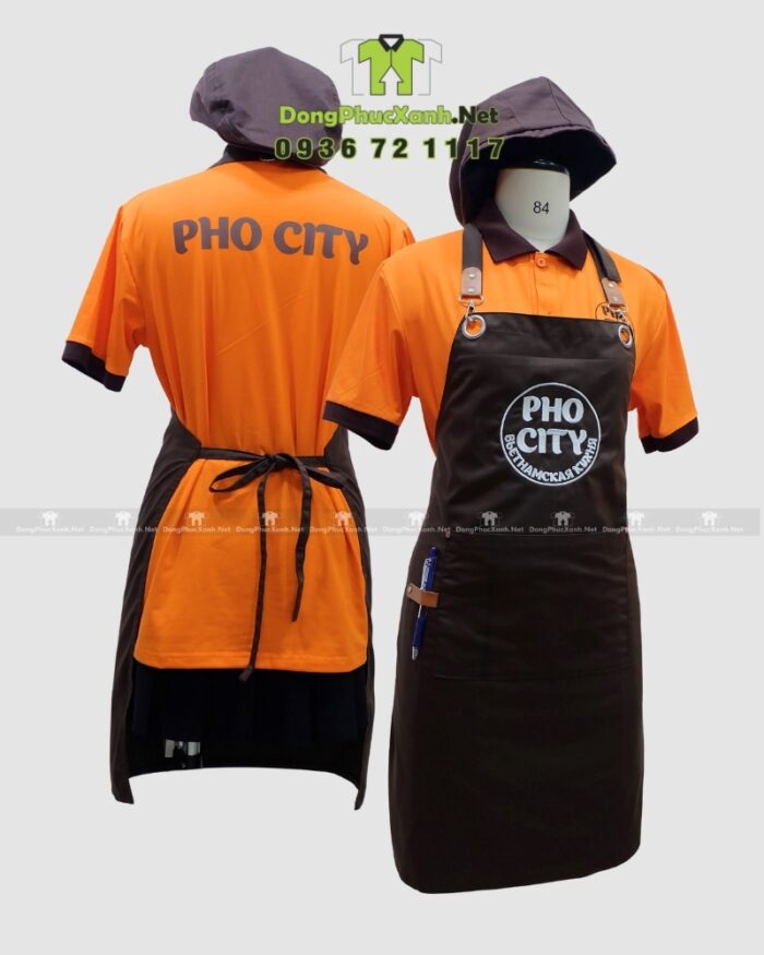 Bộ đồng phục quán ăn Pho City gồm áo thun cam và tạp dề nâu in logo nổi bật