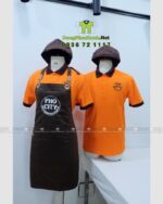 Bộ đồng phục quán ăn Pho City gồm áo thun cam và tạp dề nâu in logo nổi bật