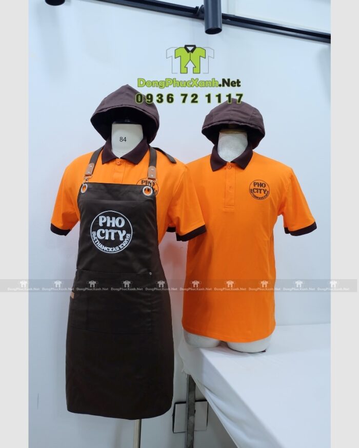 Bộ đồng phục quán ăn Pho City gồm áo thun cam và tạp dề nâu in logo nổi bật