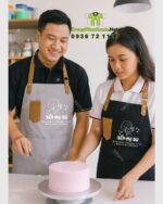 Tạp dề nhân viên Bếp Mẹ Bơ màu đen và kem có túi