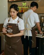Tạp dề nhân viên quán ăn Kuksu màu nâu dáng dài in logo