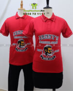 Áo thun đồng phục Jenny’s Barber Shop màu đỏ in logo lớn trước ngực.