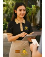 Đồng phục quán cafe Mango Kids áo polo đen và tạp dề kaki be.