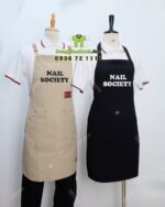 Tạp dề đồng phục thiết kế đen và kem, phối da và khóa gài, in logo Nail Society